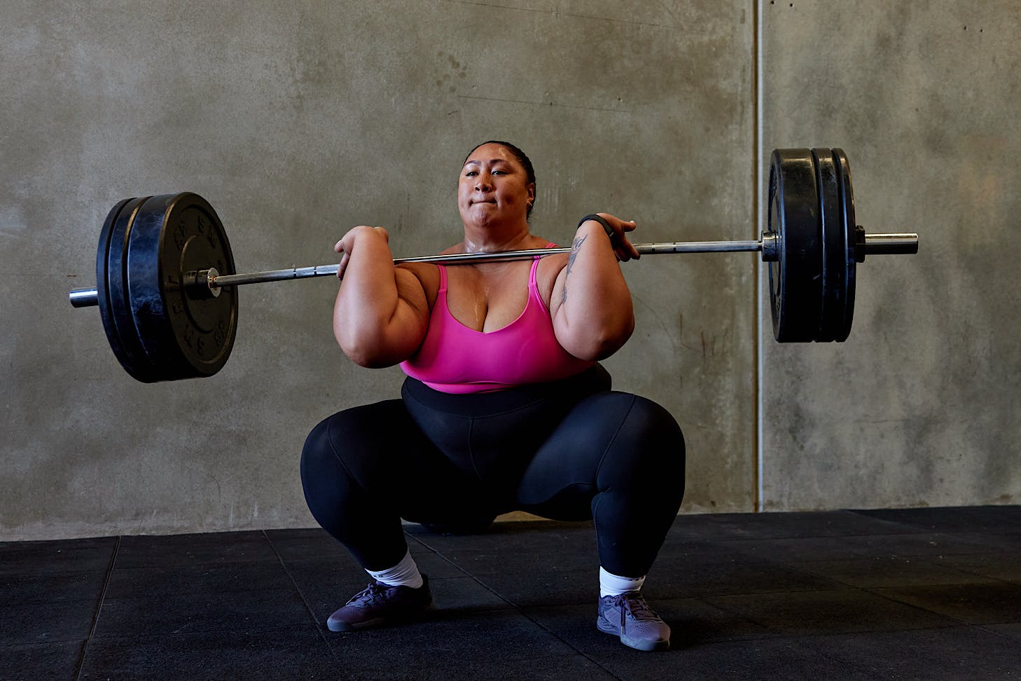 Lilz powerlifts while wearing a pink sports bra and a pair of black REP leggings by LSKD.